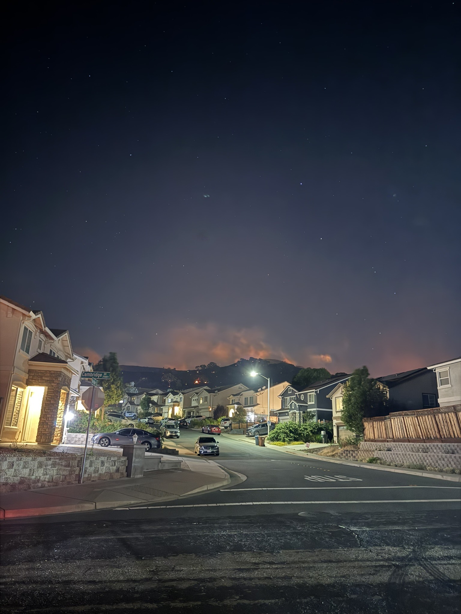 A quiet Japanese street corner at night with warm light and deep blue sky.