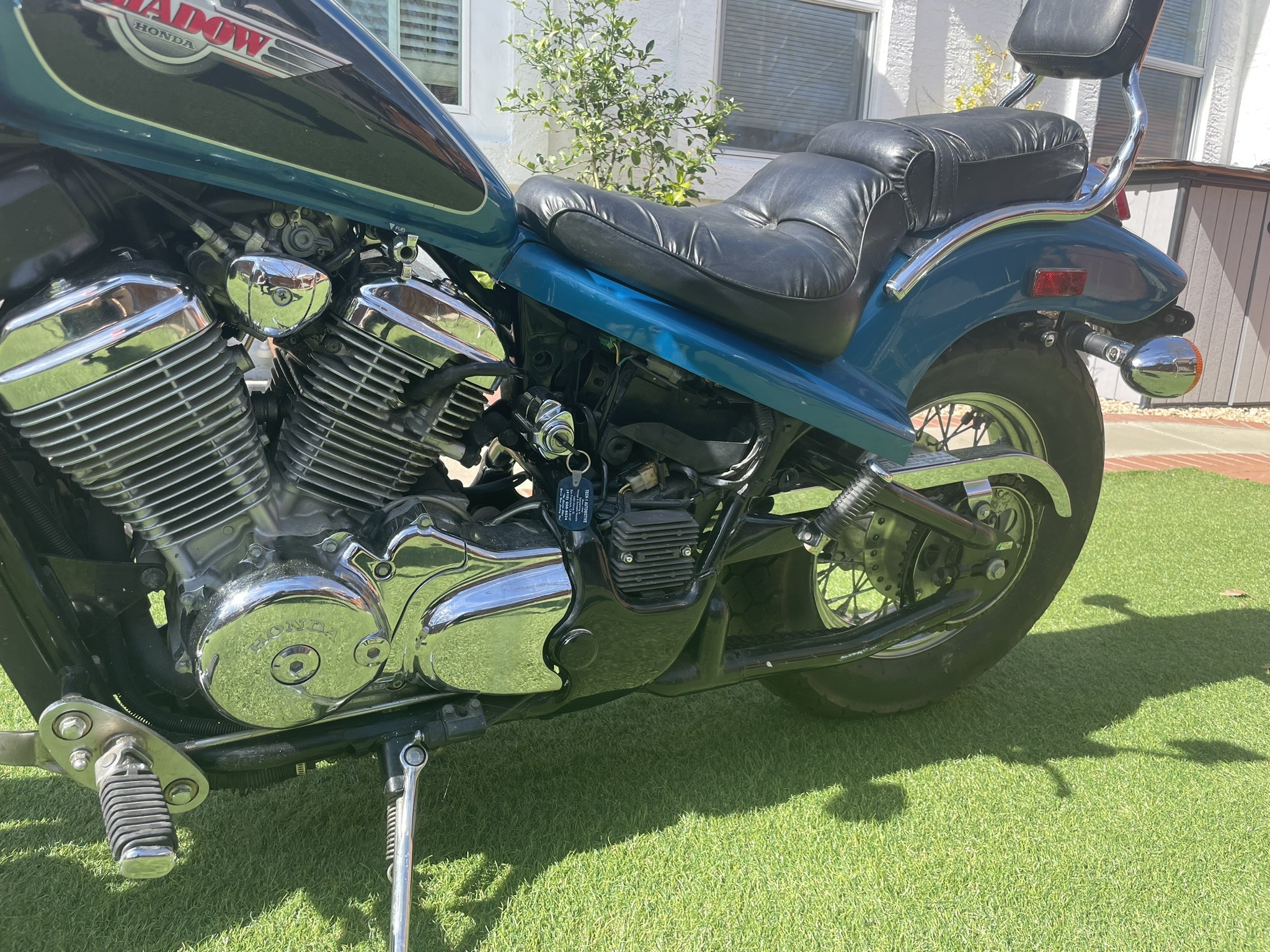 Blue motorcycle parked on grass in daylight.