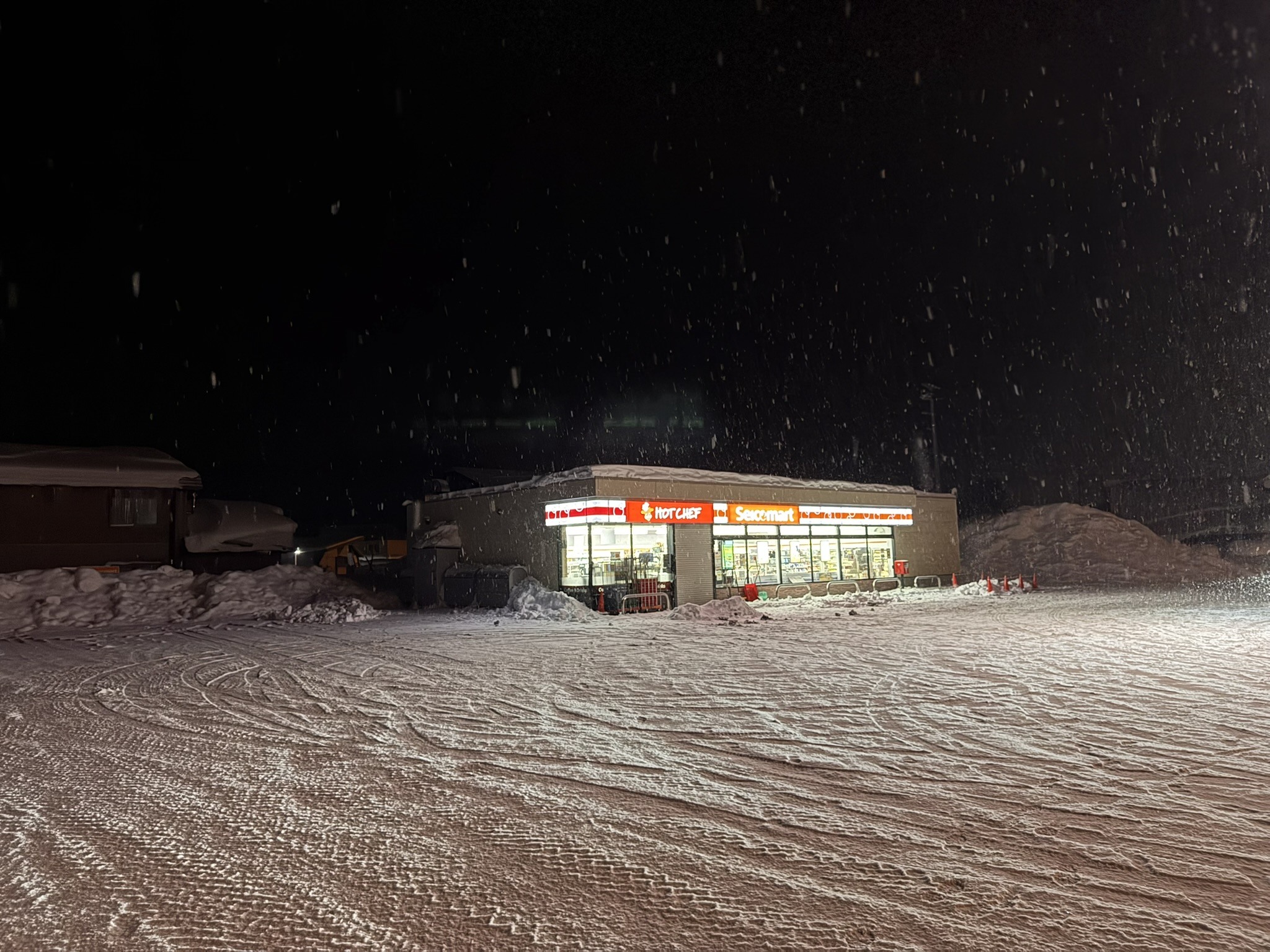 Small roadside stop lit at night in a snowy landscape.